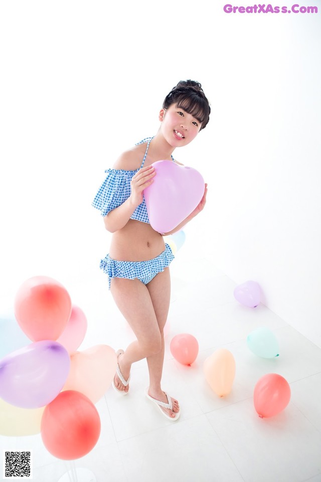 A woman in a bikini holding a heart shaped balloon.