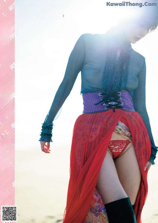 A woman in a red skirt and black boots on a beach.