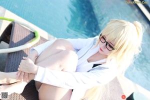 A woman in a black and white bathing suit sitting by a pool.