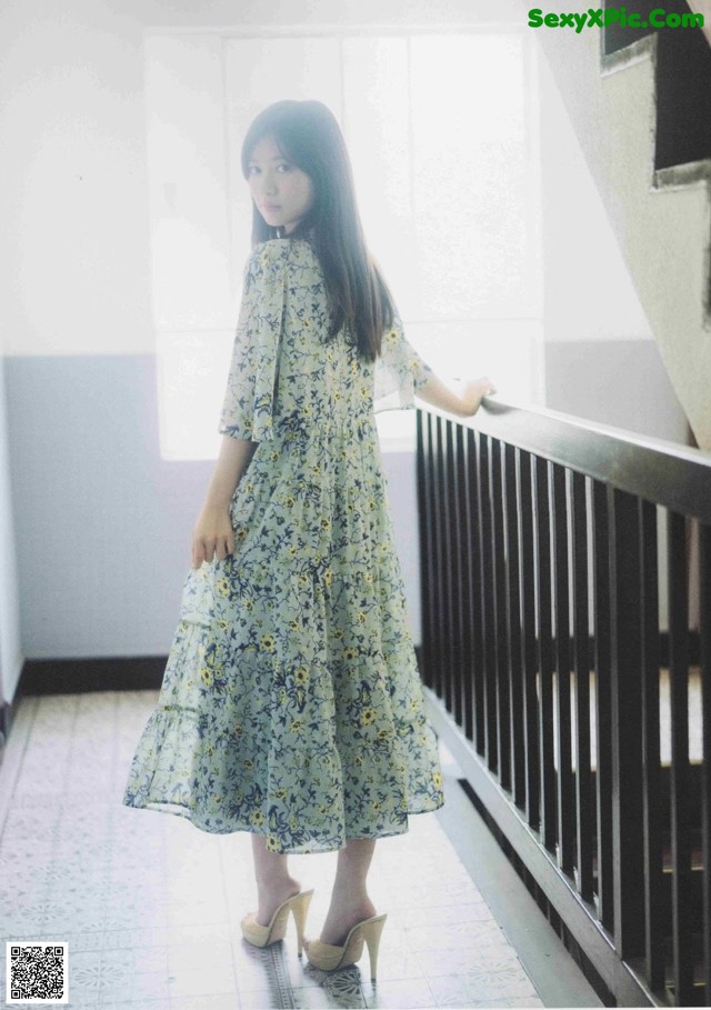 A woman in a floral dress standing on a stairwell.