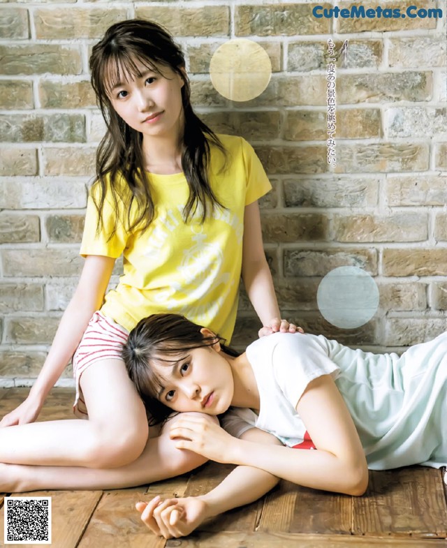 A couple of young women laying on top of a wooden floor.