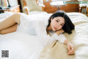 A woman sitting on a bed looking at her phone.