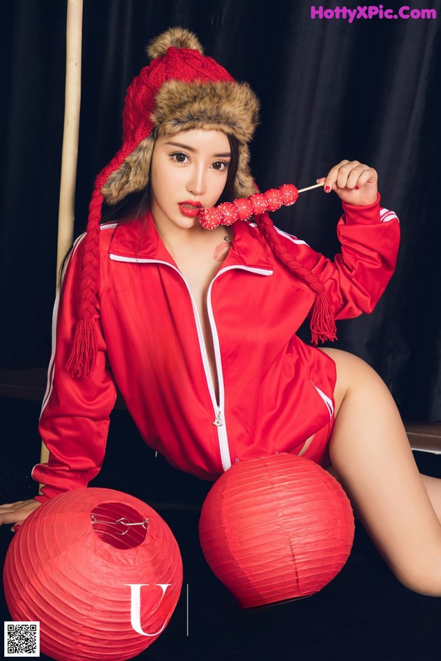 A woman in a red jacket and hat sitting on a chair.