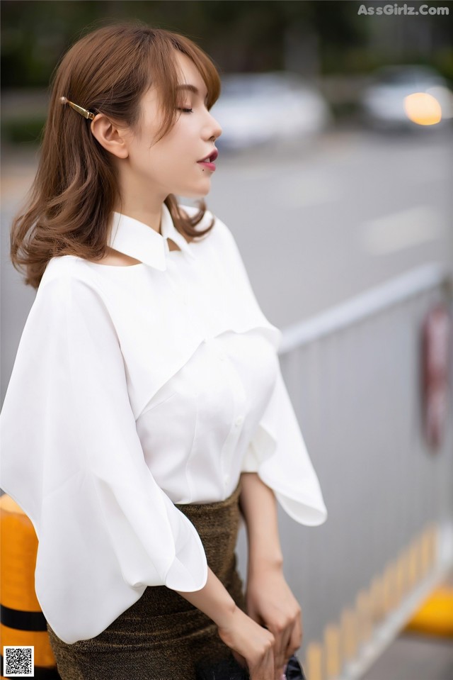 A woman wearing a white blouse and a brown skirt.