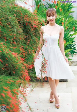 A woman in a white dress standing in front of a blue door.