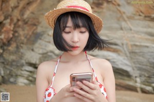 A woman in a red and white bikini and a straw hat.