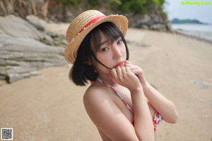 A woman in a red and white bikini standing on a beach.