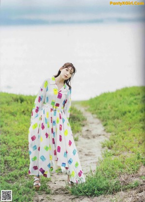 A woman in a blue dress is standing on a bridge.