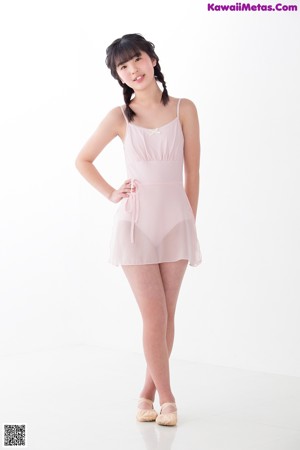 A young girl in a pink leotard and pointe shoes.