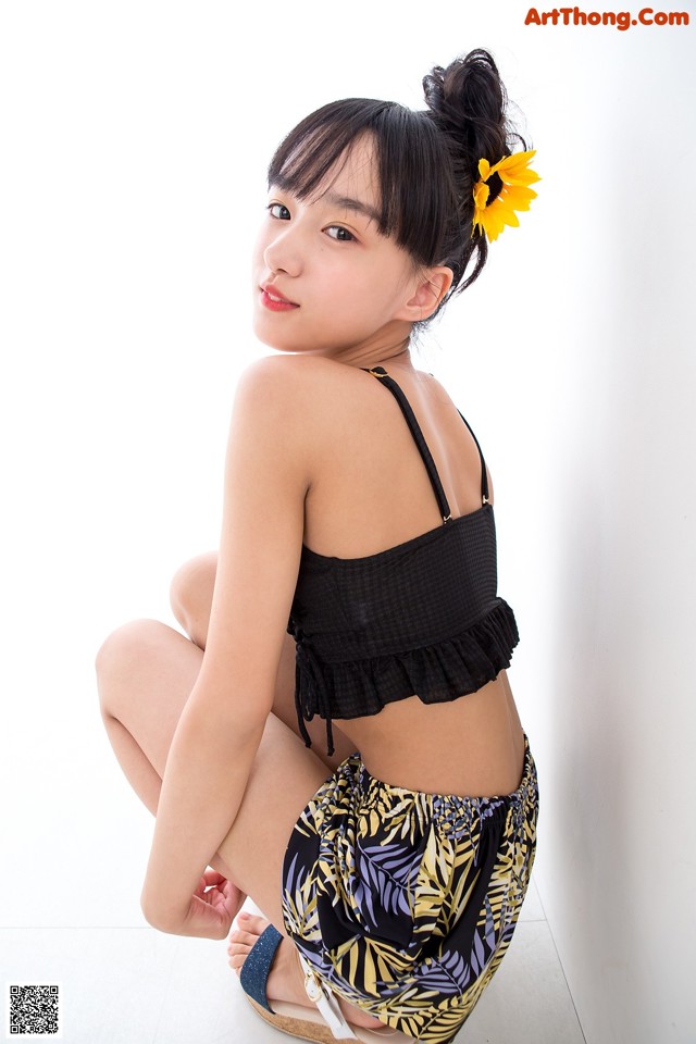 A woman sitting on the floor with a sunflower in her hair.