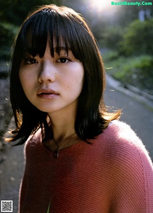A woman in a pink sweater and a floral skirt.