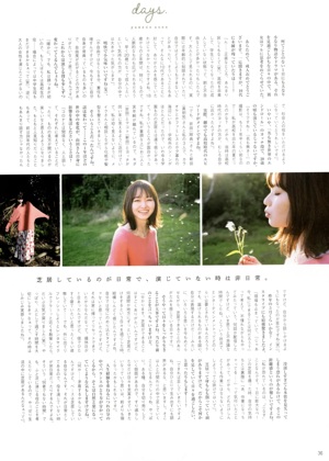 A woman in a pink sweater and a floral skirt is dancing in the grass.