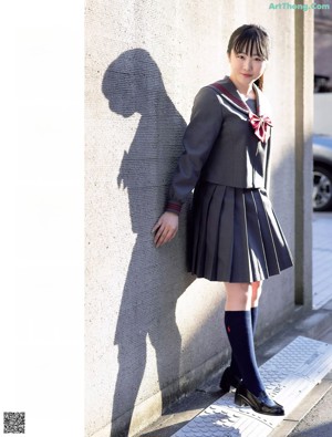 A young woman in a school uniform smiles at the camera.