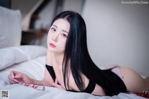 A woman sitting on a bed with her legs crossed.