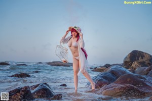 A woman in a white bikini sitting on a beach.