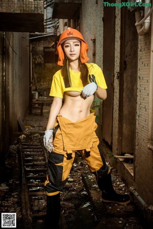 A woman in a yellow shirt and orange hard hat posing for a picture.