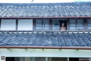 A naked woman standing in front of a green wall.