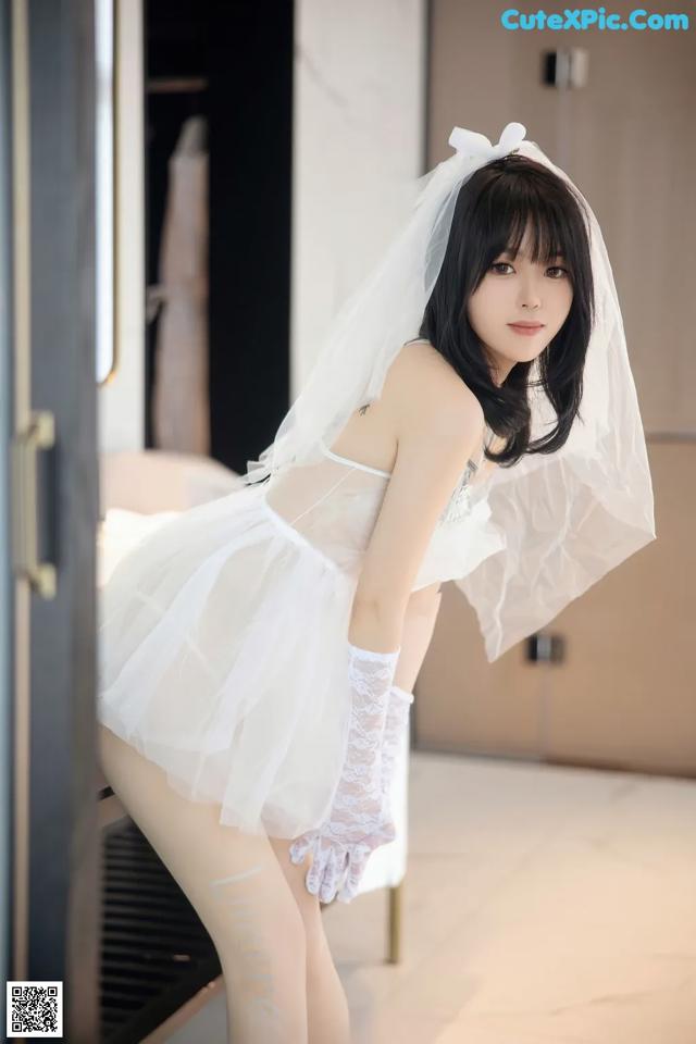 A woman in a white dress and a veil posing for a picture.