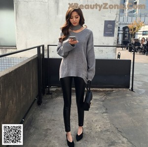 A woman in a pink sweater and panties posing for a picture.