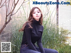 a woman wearing a black hoodie and jeans standing in front of a building