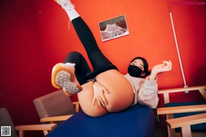 A woman sitting on top of a bed wearing a face mask.