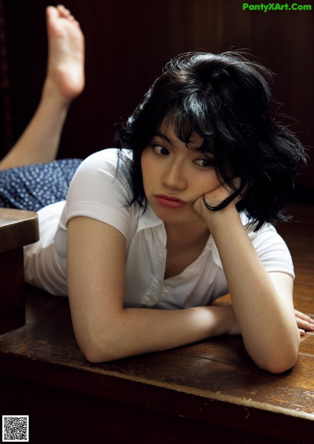 A woman laying on a wooden table with her legs crossed.