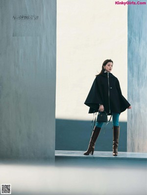 A woman in a black coat holding a brown and white handbag.