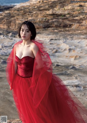 A woman in a pink dress standing on a bridge.