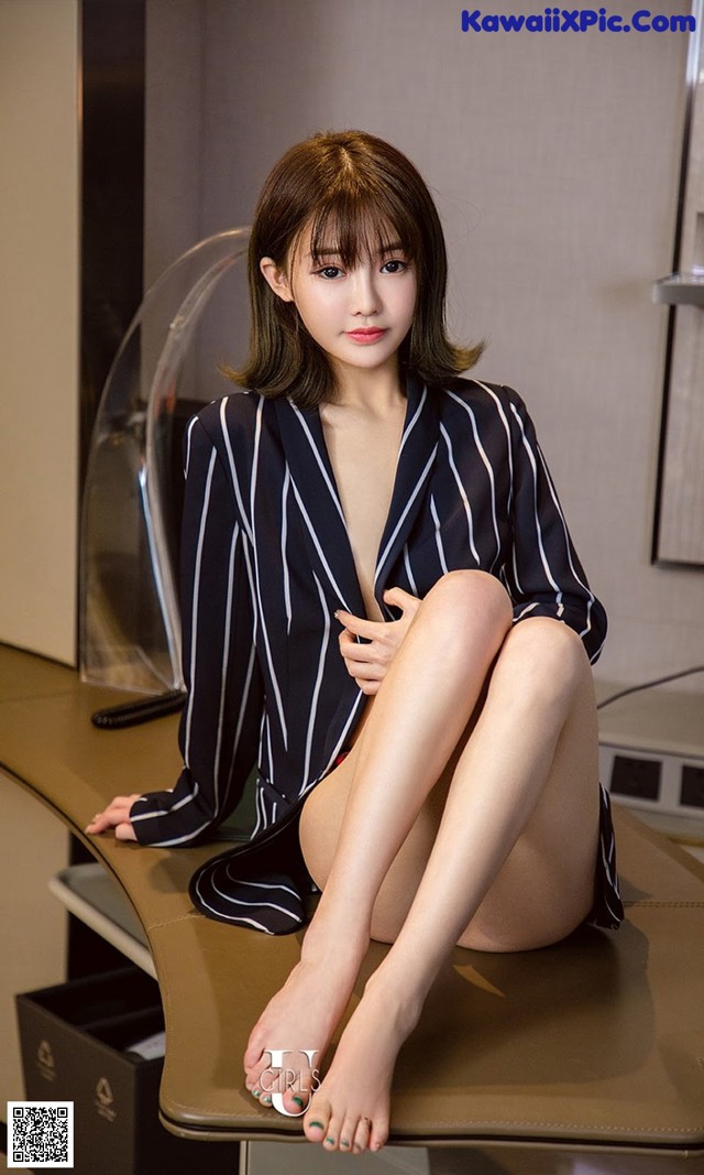 A woman sitting on top of a desk in a room.