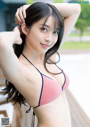 A woman in a blue bikini standing on a wooden deck.