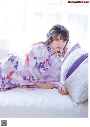 A young girl in a kimono sitting on a bed.