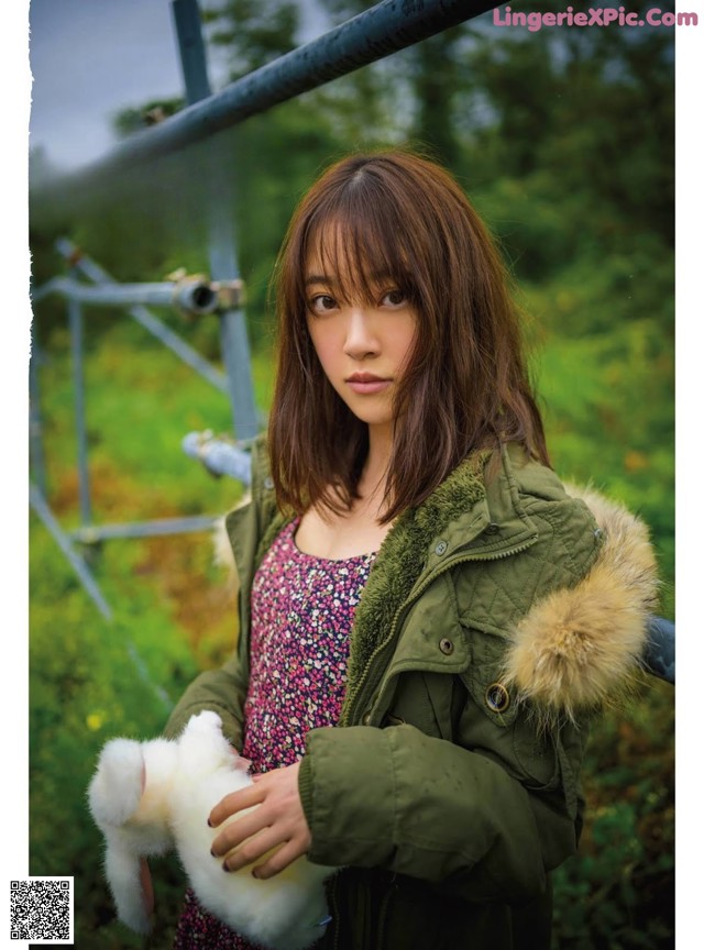 A woman in a green jacket holding a white rabbit.