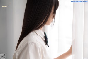 A young girl in a school uniform is posing for a picture.