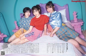 A group of three women sitting on top of a bed.